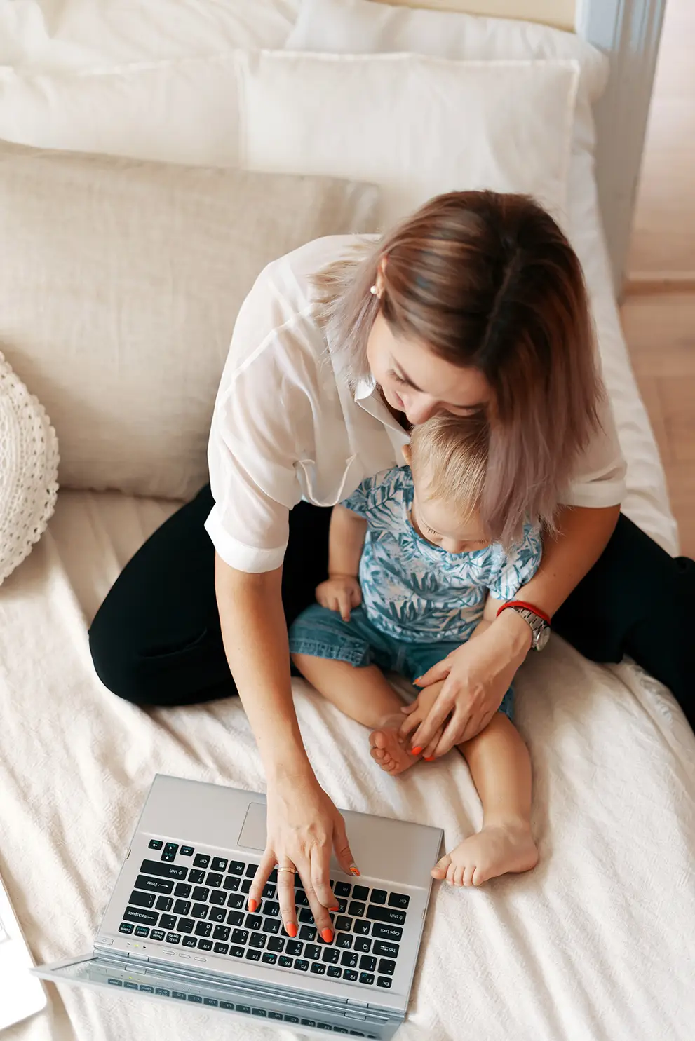 Photo d'un parent utilisant un PC portable avec un bébé dans les bras